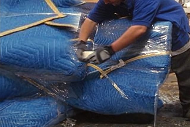 A man in blue shirt and gloves working on a pile of blue bags.