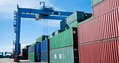 A crane is lifting cargo containers from the docks.