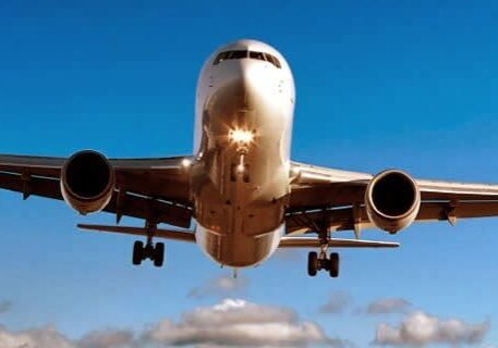 A large airplane flying through the air with its landing gear down.