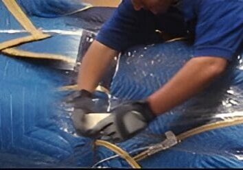 A man is cutting metal with a pair of gloves.