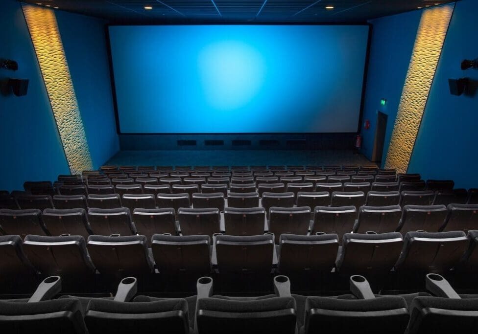 A movie theater with rows of seats and a large screen.